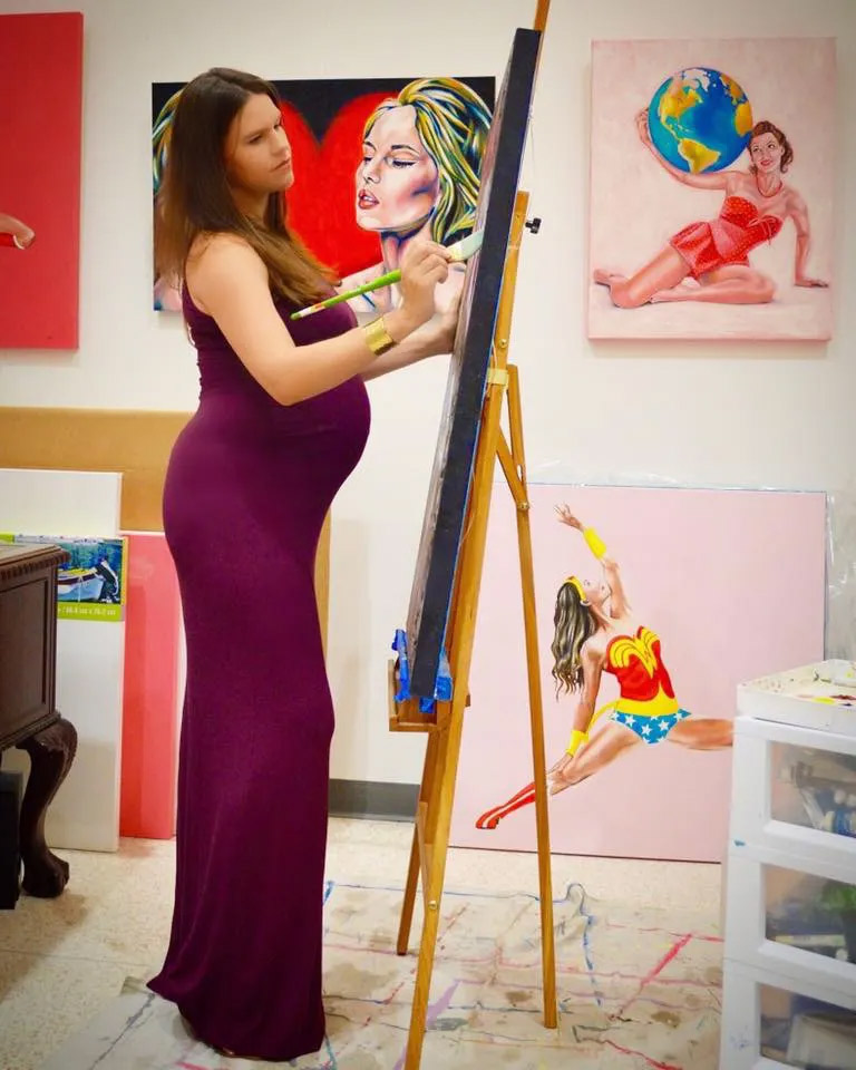 Pregnant artist painting in her studio.